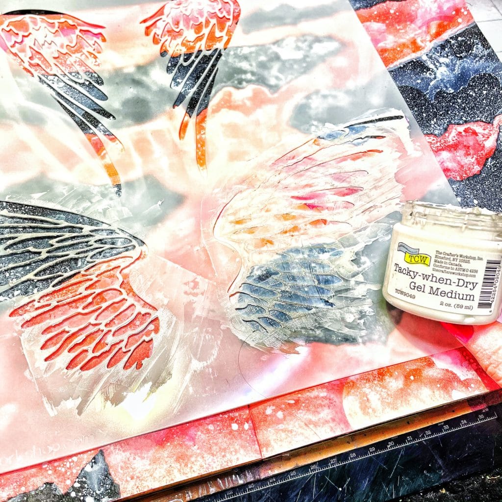 even layer of TCW 9049 Tacky When Dry Dry Gel Medium through 12x12 TCW616 Angel Wings Stencil with a palette knife