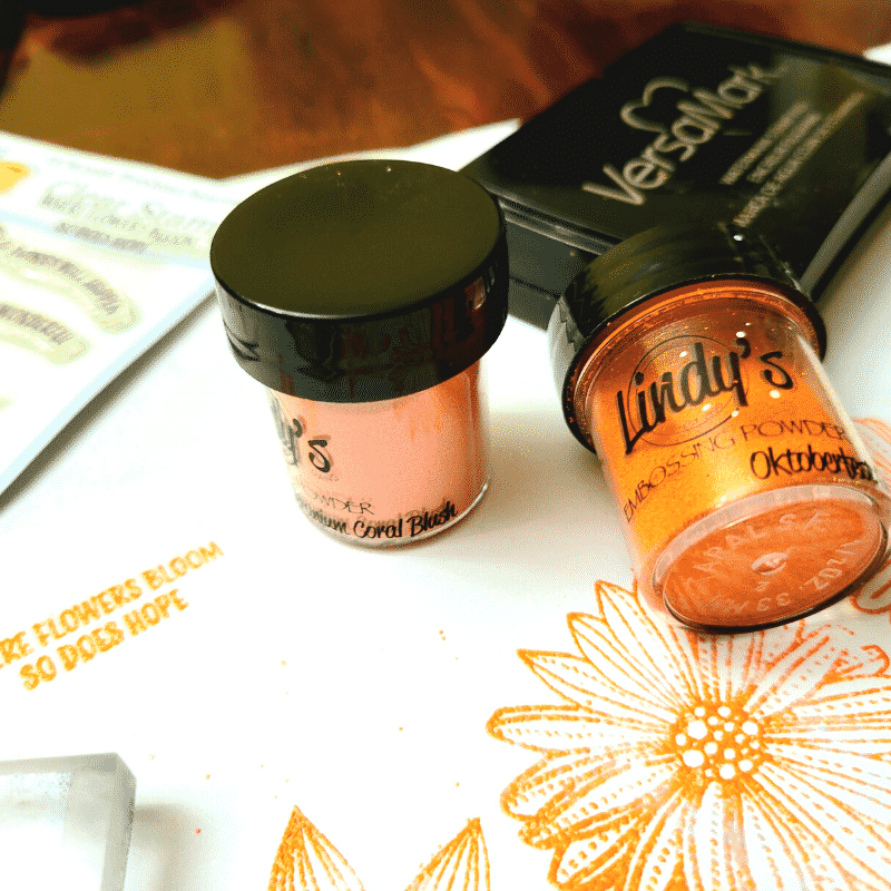 Close up image showing the stamped sentiment and flowers heat embossed with orange and coral embossing powders.